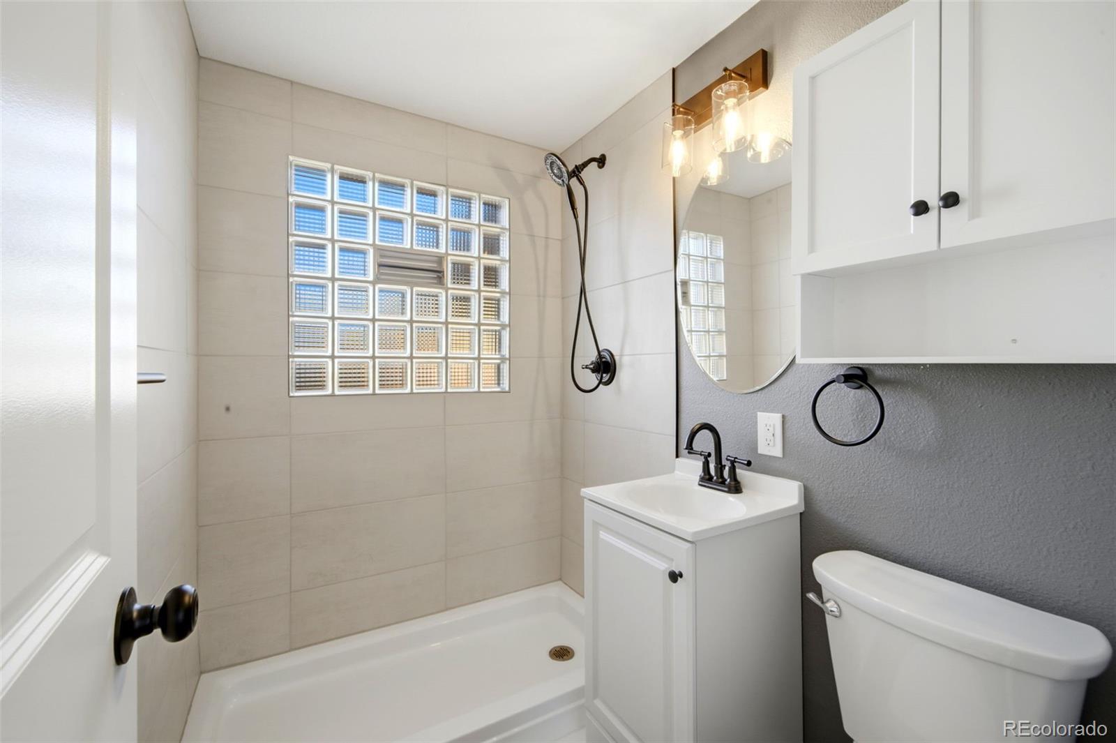 4933 Steele Street Denver, CO 80216 - Photo 16 of 31 a bathroom with a sink toilet and shower