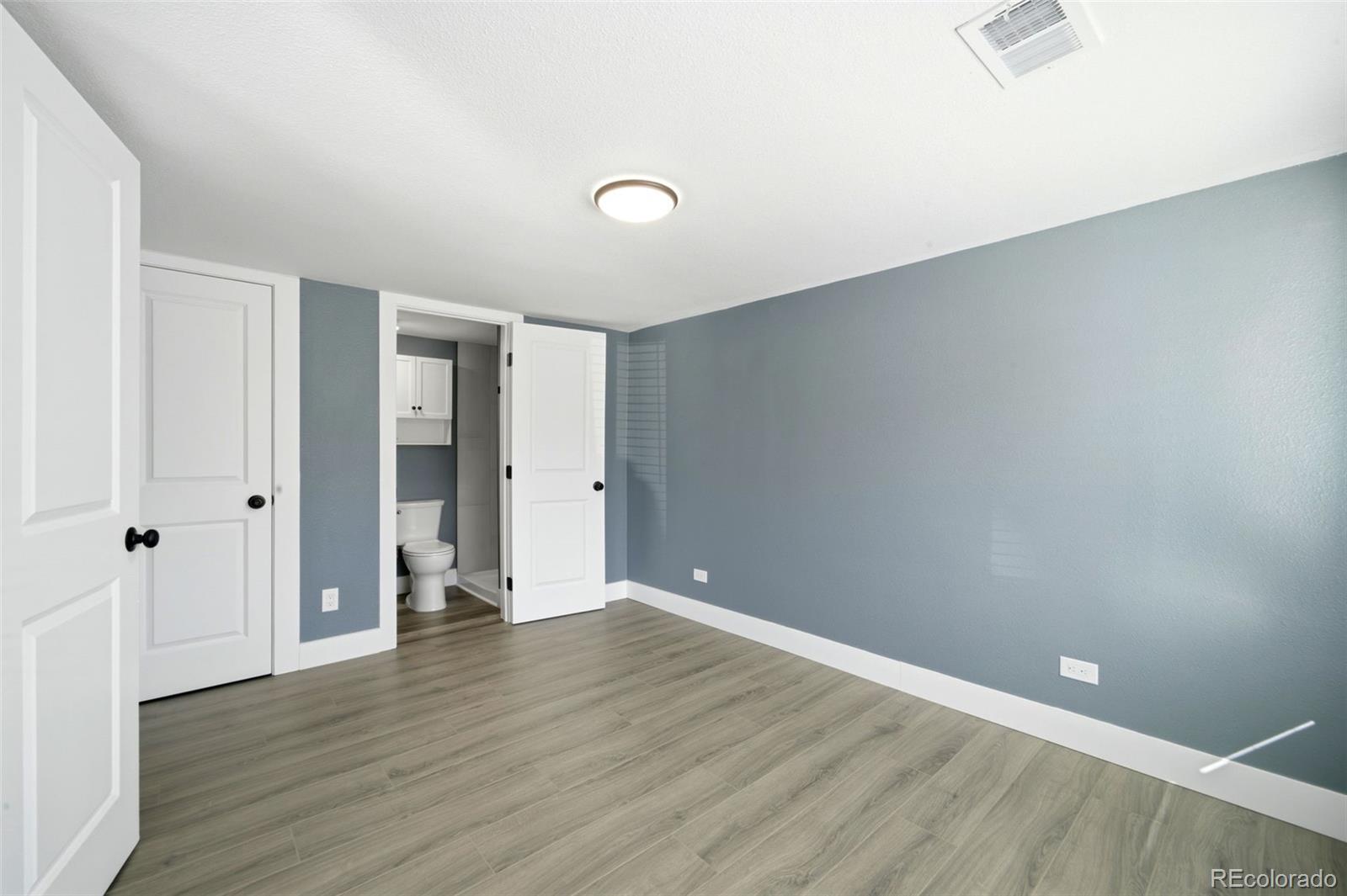 4933 Steele Street Denver, CO 80216 - Photo 17 of 31 a view of an empty room with wooden floor and closet