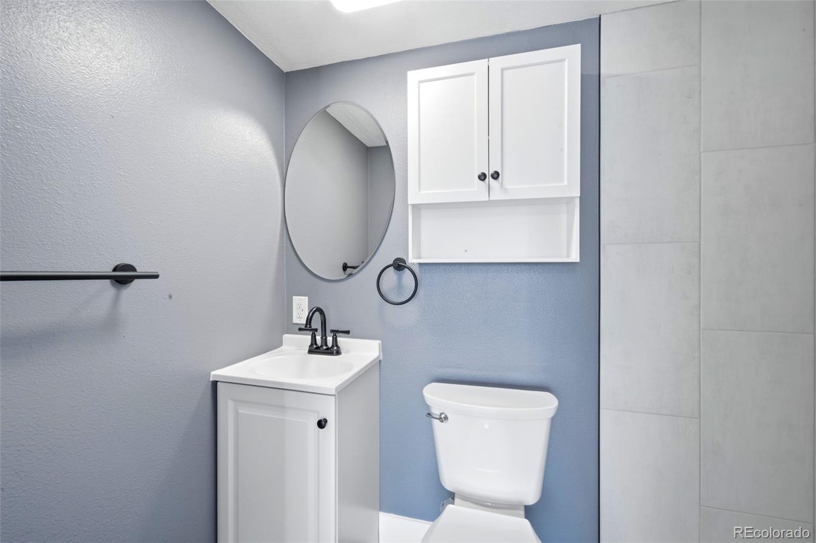 4933 Steele Street Denver, CO 80216 - Photo 19 of 31 a bathroom with a toilet sink and mirror