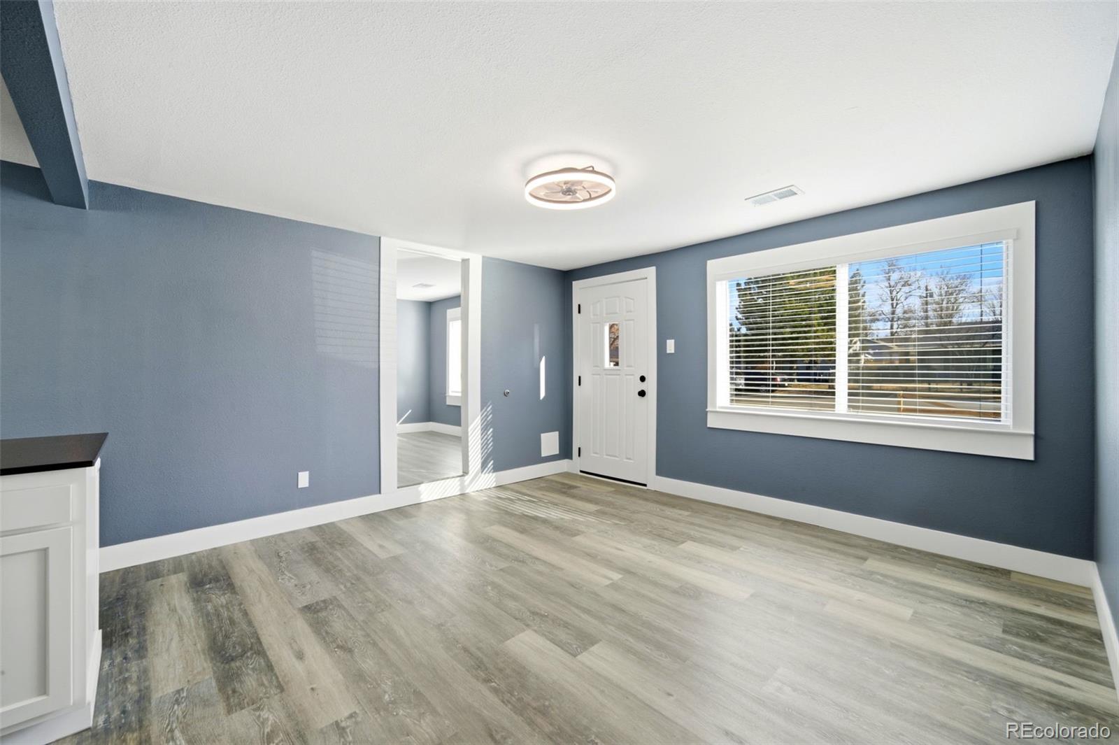 4933 Steele Street Denver, CO 80216 - Photo 5 of 31 a view of an empty room with wooden floor and a window