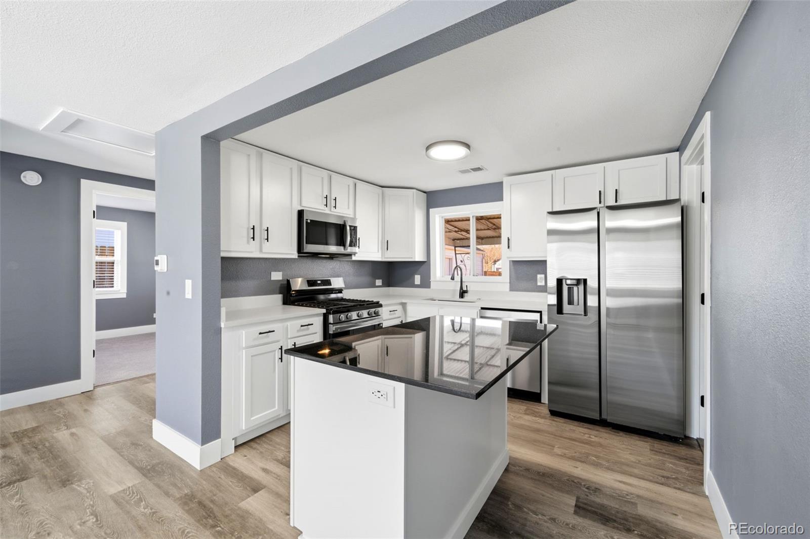 4933 Steele Street Denver, CO 80216 - Photo 8 of 31 a kitchen with stainless steel appliances granite countertop a refrigerator stove and microwave
