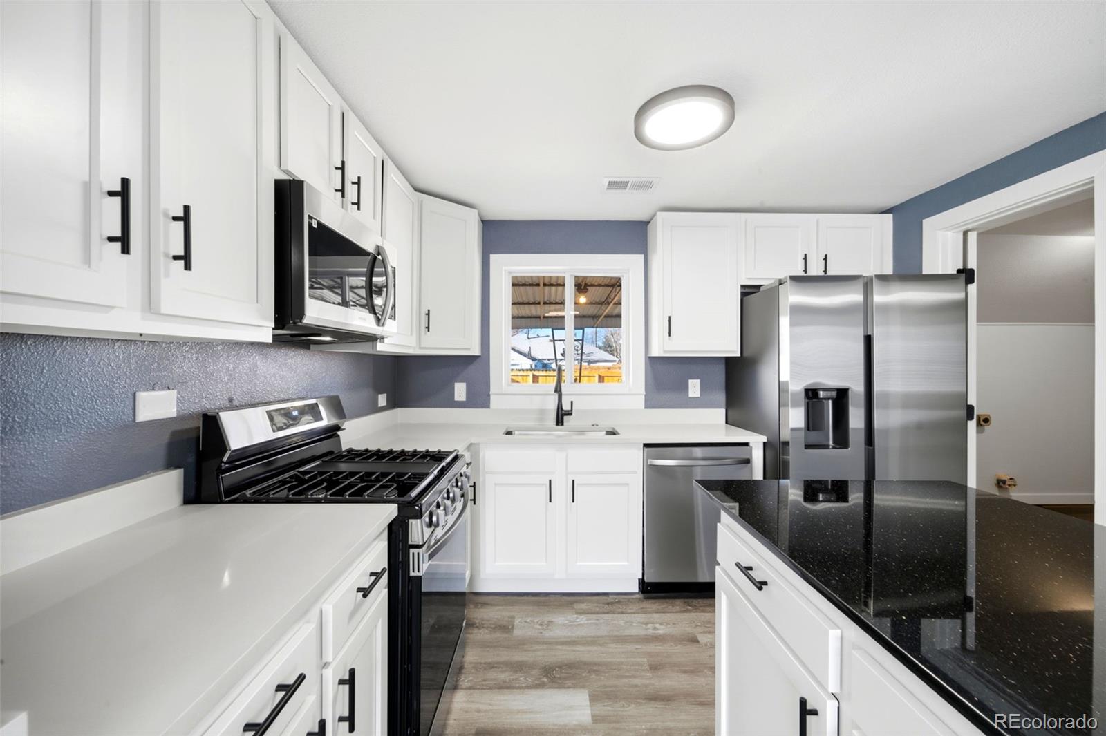 4933 Steele Street Denver, CO 80216 - Photo 9 of 31 a kitchen with stainless steel appliances granite countertop a refrigerator a stove and a sink