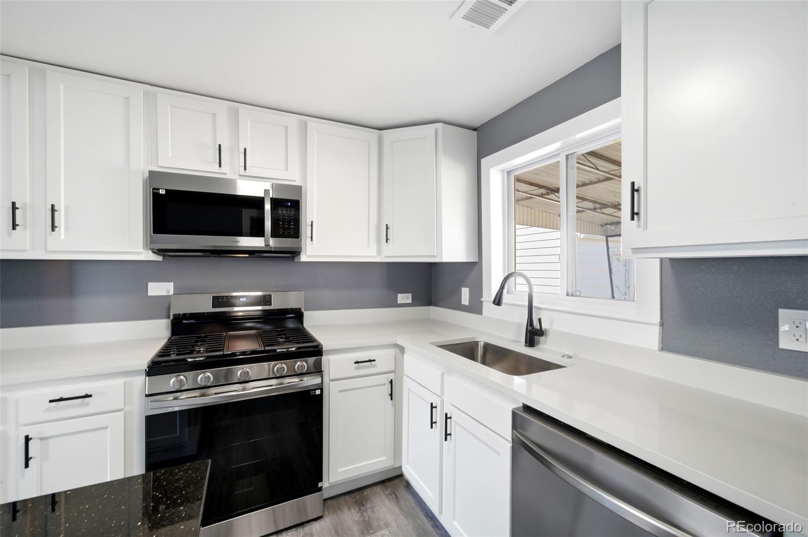 4933 Steele Street Denver, CO 80216 - Photo 10 of 31 a kitchen with stainless steel appliances white cabinets and a stove top oven
