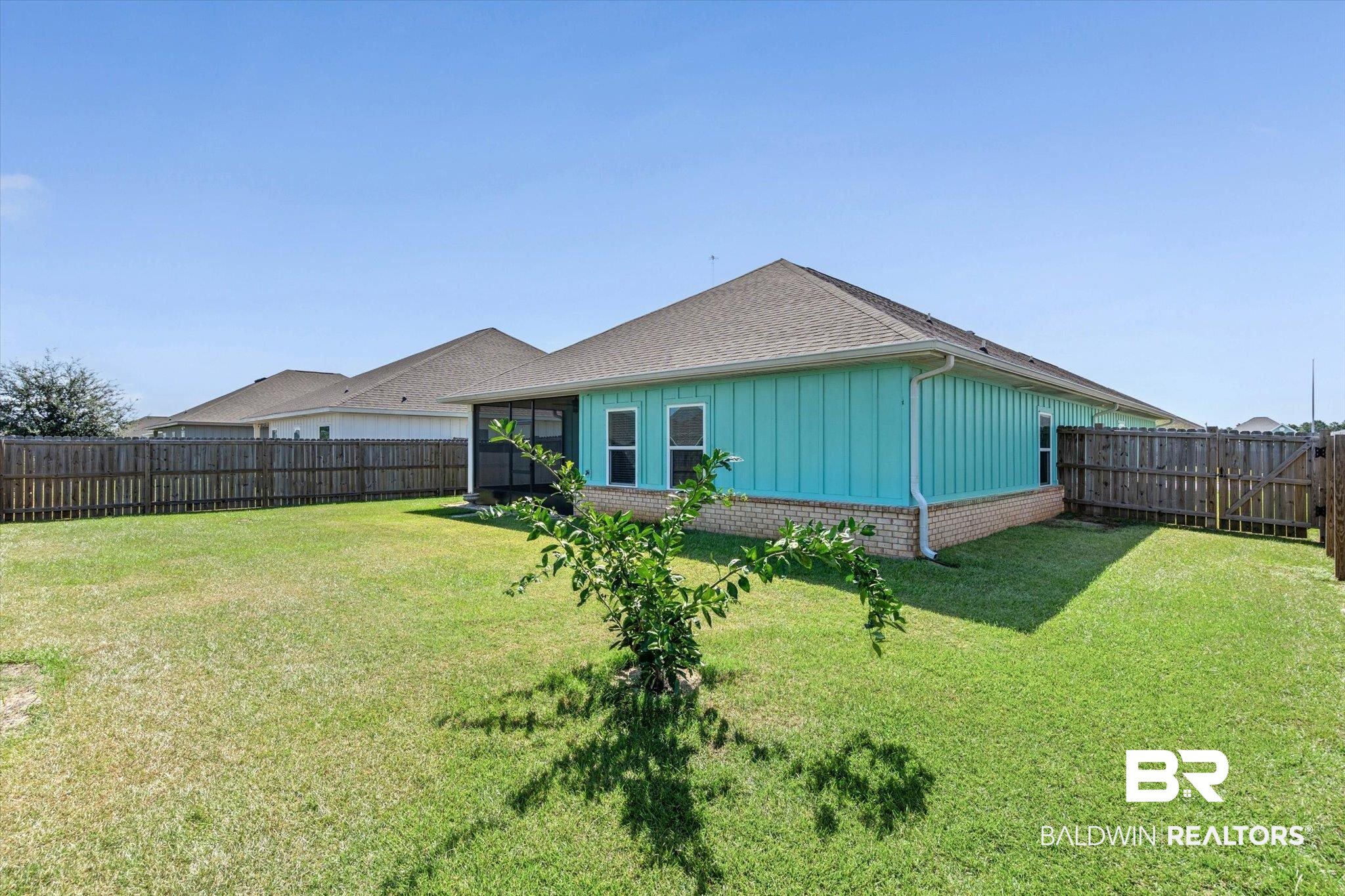 22976 Lieutenant Avenue Foley, AL 36535 - Photo 20 of 30 Back of house featuring a fenced backyard, brick siding, a shingled roof, and board and batten siding