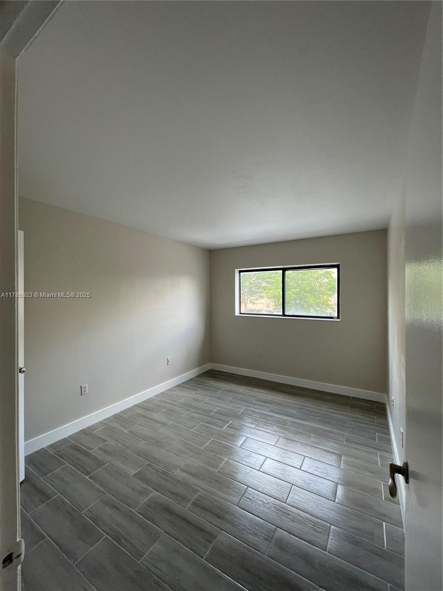 West End Miami, FL 33193 - Photo 10 of 12 an empty room with wooden floor and windows