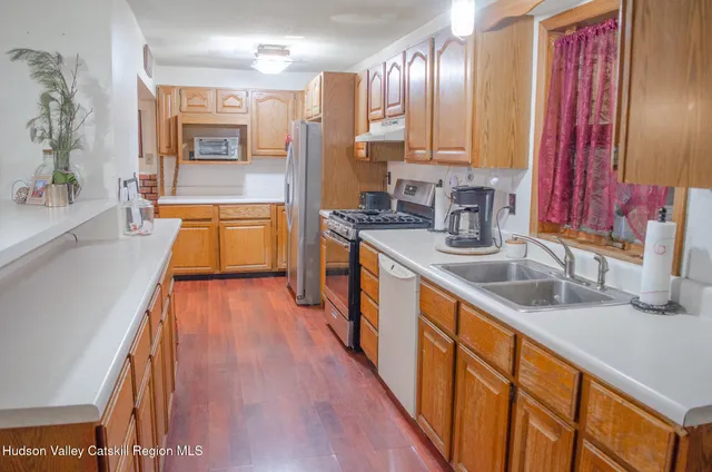 a large kitchen with stainless steel appliances a large counter top a stove a sink and a refrigerator