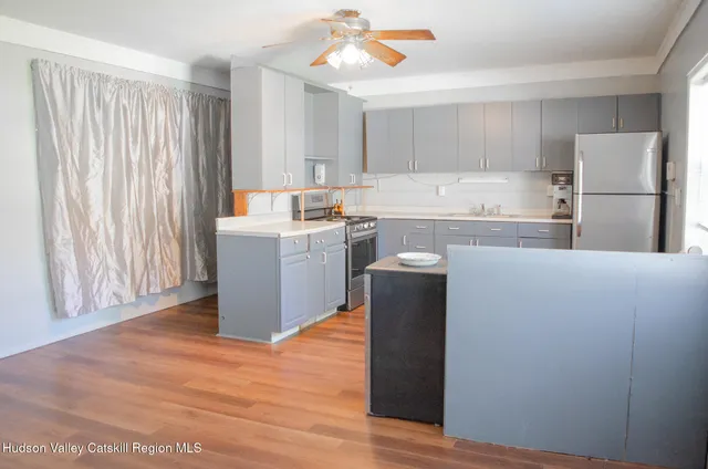 a kitchen with kitchen island a sink a stove a refrigerator and white cabinets
