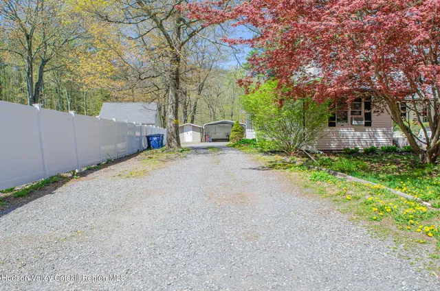 a backyard of a house with plants and trees with wooden fence