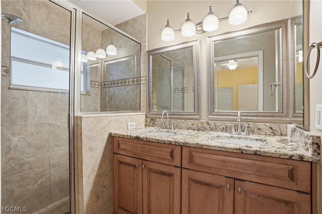 10730 Rio Mar Circle Estero, FL 33928 - Photo 18 of 47 a bathroom with a granite countertop sink a large mirror and a shower