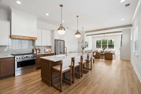 a large kitchen with lots of counter space a sink appliances and living room view