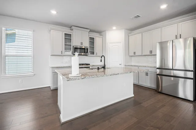 a kitchen with stainless steel appliances granite countertop a refrigerator sink and white cabinets