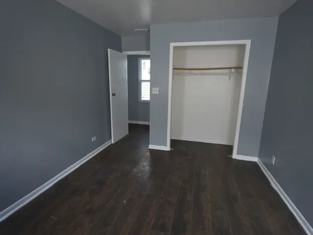 an empty room with wooden floor closet and windows
