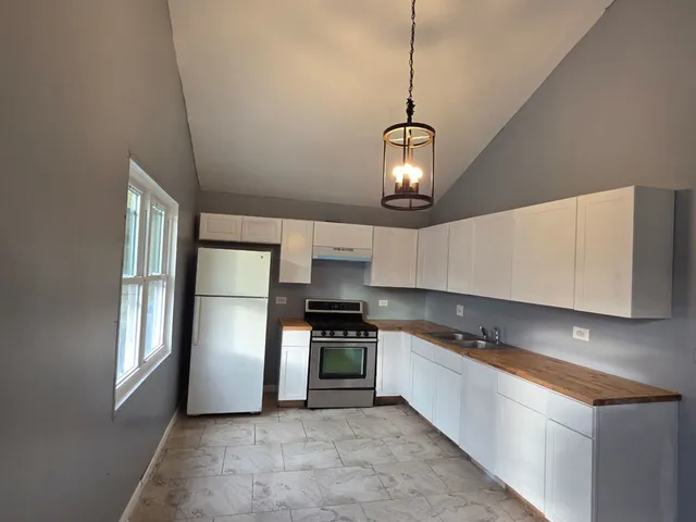 a kitchen with stainless steel appliances a refrigerator a sink and white cabinets