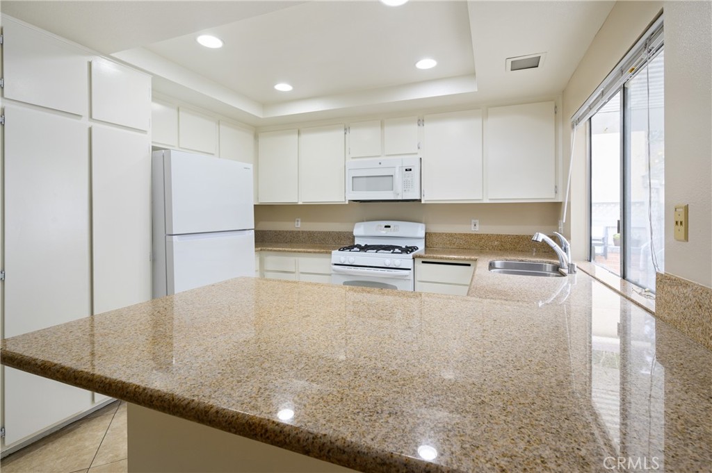 25 Sweet Rain Irvine, CA 92614 - Photo 9 of 45 a kitchen with kitchen island a counter top space a stove a refrigerator white cabinets and a refrigerator