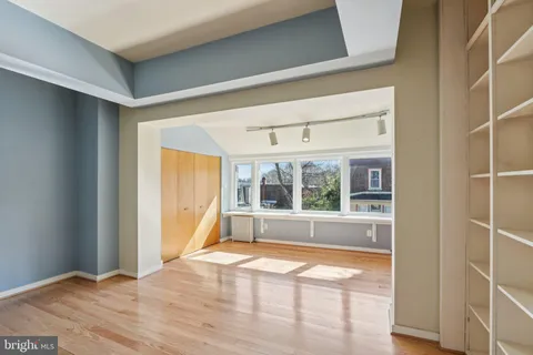 an empty room with wooden floor fan and windows