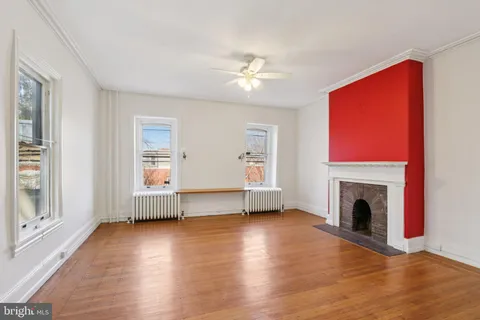 an empty room with wooden floor closet and windows