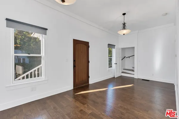 a view of an empty room with a window and wooden floor