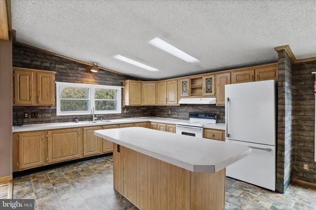 a kitchen with stainless steel appliances granite countertop a refrigerator a sink dishwasher a stove and white countertops with wooden floor