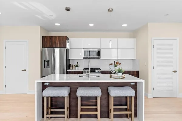 a kitchen with stainless steel appliances granite countertop a dining table chairs refrigerator and cabinets