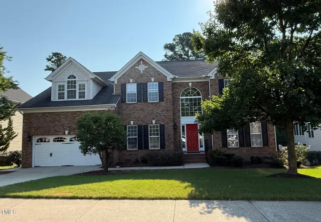 a front view of a house with a garden and trees