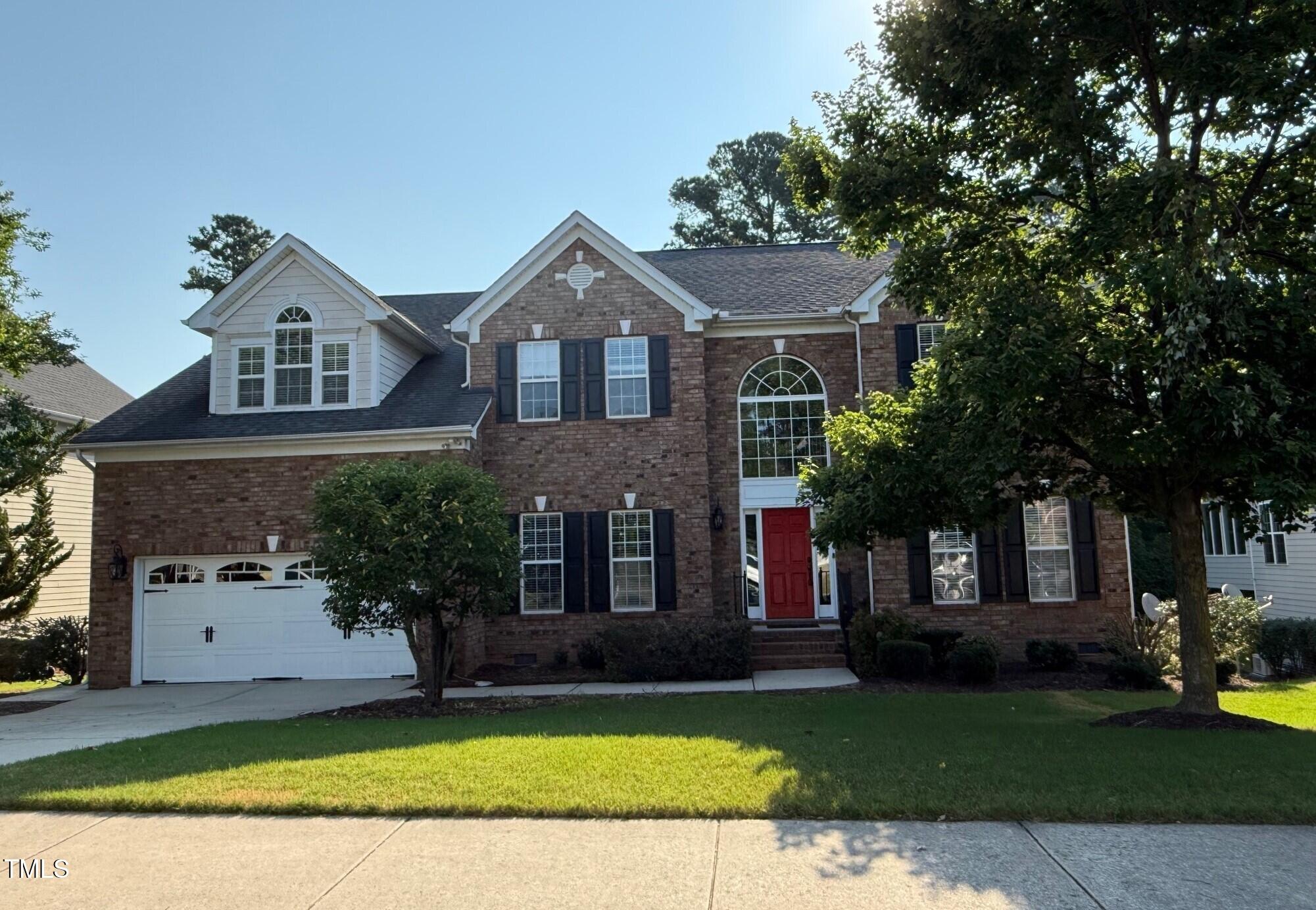 a front view of a house with a garden and trees