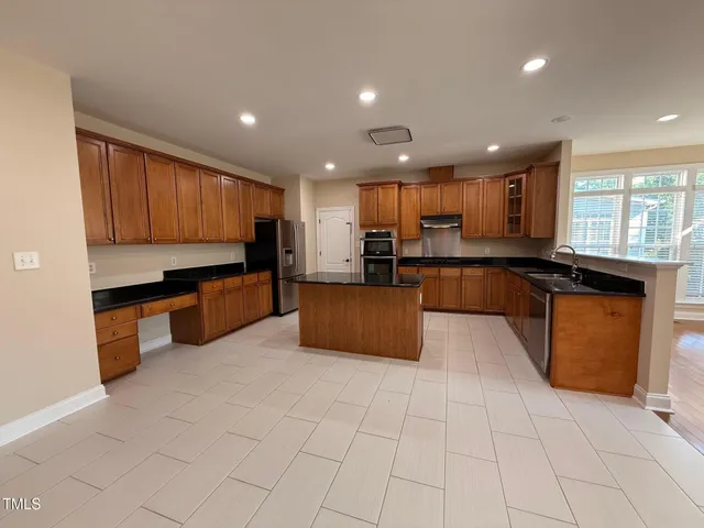 a large kitchen with stainless steel appliances granite countertop a stove a sink and a microwave