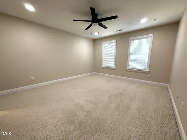 an empty room with windows and ceiling fan