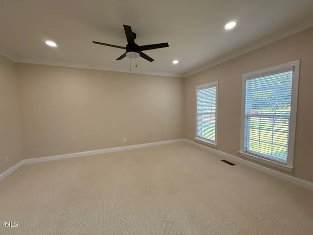 an empty room with windows and fan