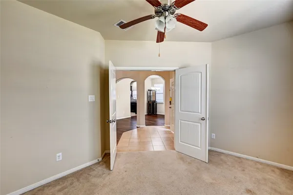 an empty room with ceiling fan and wooden floor