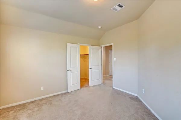an empty room with chandelier fan and windows