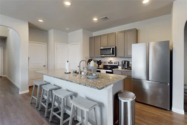 a kitchen with kitchen island granite countertop a refrigerator a stove a sink and a refrigerator