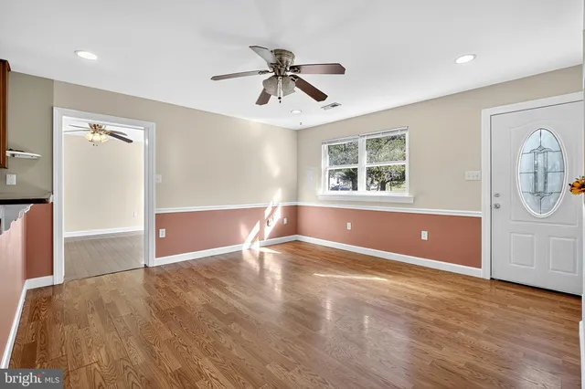 an empty room with wooden floor fan and windows