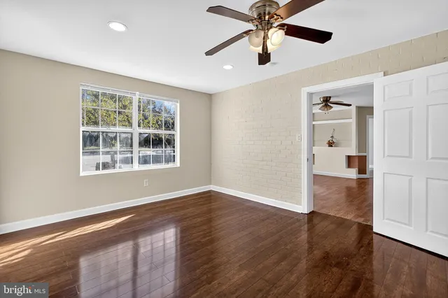 a view of an empty room with window and wooden floor