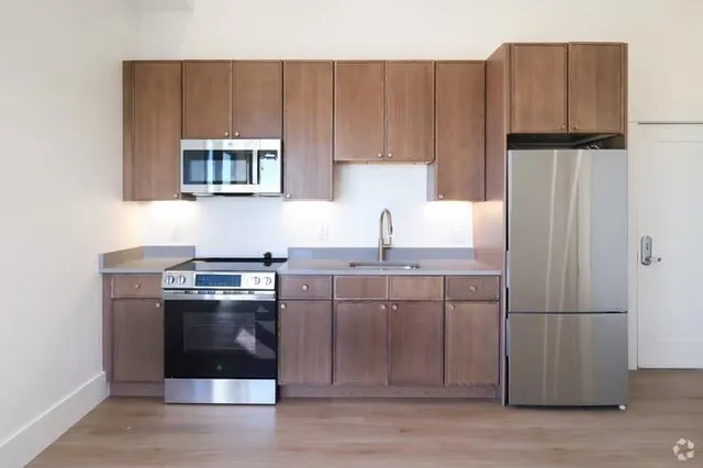 a kitchen with stainless steel appliances granite countertop a refrigerator a stove a sink and a microwave