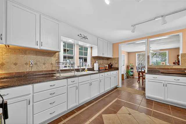 a large white kitchen with stainless steel appliances granite countertop a sink and cabinets