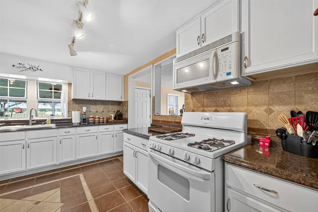 a kitchen with granite countertop cabinets and white appliances