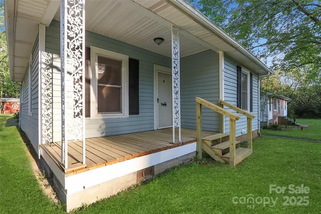 a view of backyard of house with wooden deck and outdoor seating