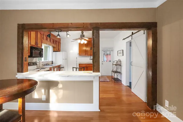 a living room with stainless steel appliances furniture a large window and a wooden floor