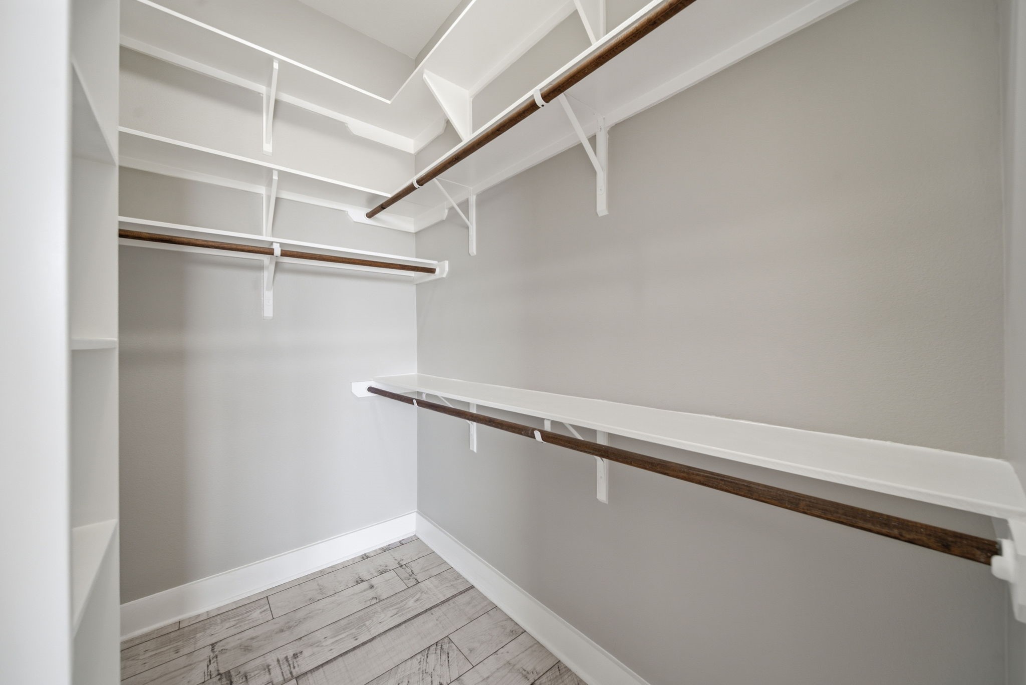 1814 Thompson Street Houston, TX 77007 - Photo 15 of 37 Spacious secondary walk-in closet in the primary suite, thoughtfully designed with multiple shelving units and hanging rods for maximum storage and organization. Finished with light wood flooring and neutral tones, it offers a clean, modern space that enhances everyday functionality and appeal.