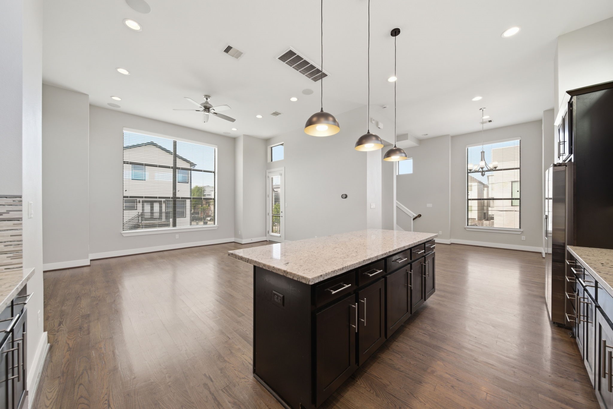 1814 Thompson Street Houston, TX 77007 - Photo 2 of 37 Open-concept living area showcasing rich hardwood floors, expansive windows that flood the space with natural light, and a stylish modern kitchen complete with a central island and elegant pendant lighting—perfect for both everyday living and entertaining.