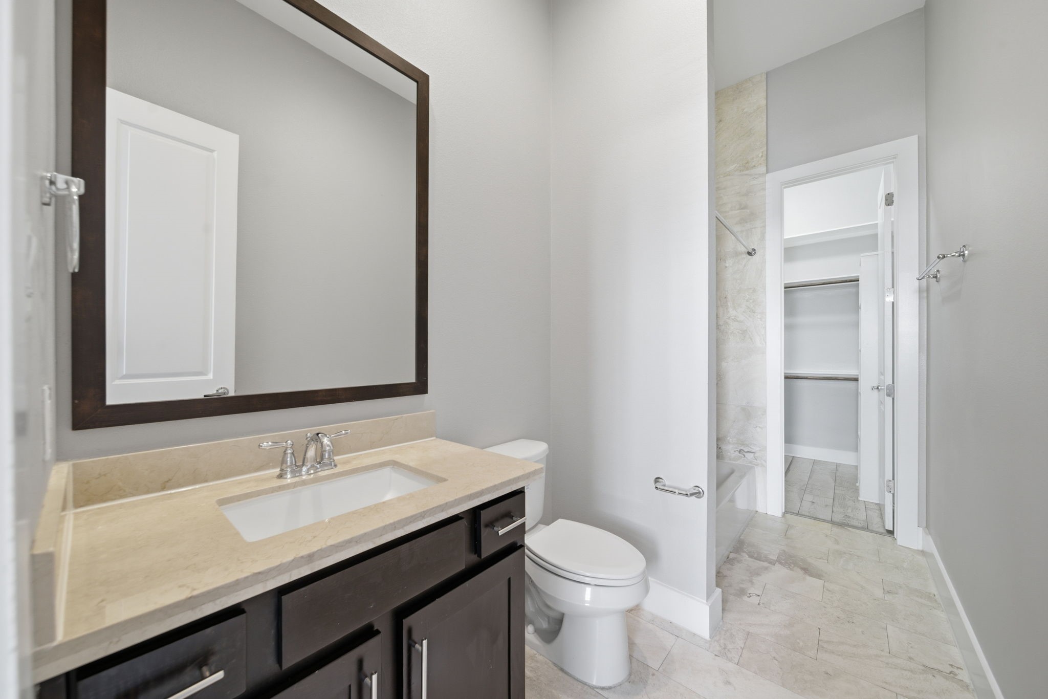 1814 Thompson Street Houston, TX 77007 - Photo 27 of 37 Modern downstairs ensuite bathroom featuring a sleek vanity with an oversized mirror, neutral tile flooring, and a private toilet. The adjacent walk-in shower showcases elegant marble accents, creating a clean, spa-like atmosphere with a spacious, contemporary feel.