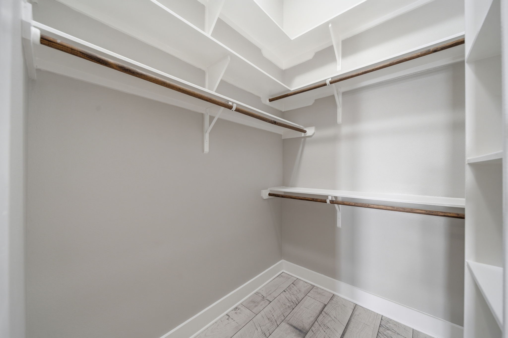 1814 Thompson Street Houston, TX 77007 - Photo 28 of 37 Spacious walk-in closet featuring custom white shelving and warm wood hanging rods, offering exceptional storage and organization. The neutral finishes and light flooring create a bright, open feel—delivering both functionality and a clean, modern aesthetic.