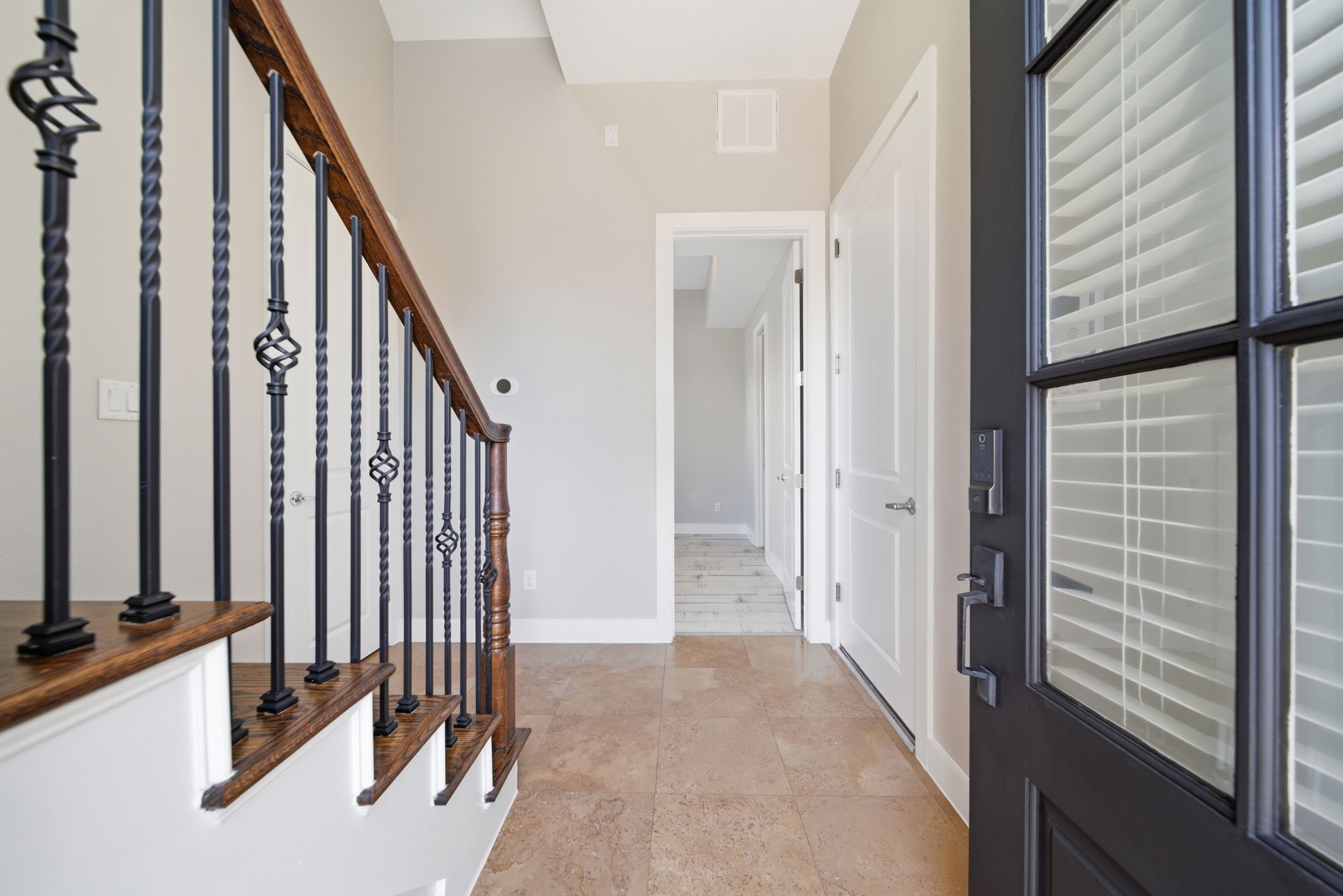 1814 Thompson Street Houston, TX 77007 - Photo 30 of 37 Welcoming entryway featuring a modern black front door with glass panels that allow for natural light. The space opens to tiled flooring and a bright hallway with white interior doors. A convenient coat closet is located to the left, and a staircase with dark wood steps and black metal railings adds a refined, modern touch.