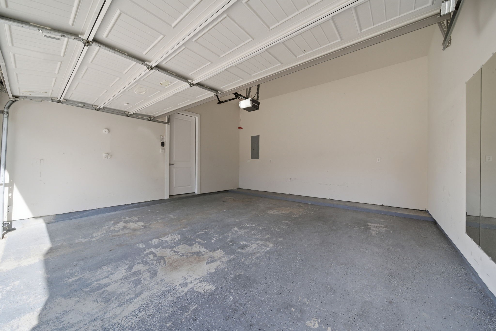 1814 Thompson Street Houston, TX 77007 - Photo 35 of 37 Spacious garage featuring a concrete floor, white walls, and an automatic garage door opener. Offering excellent versatility, this space is ideal for secure parking, additional storage, or both—providing convenience and functionality to complement modern living.