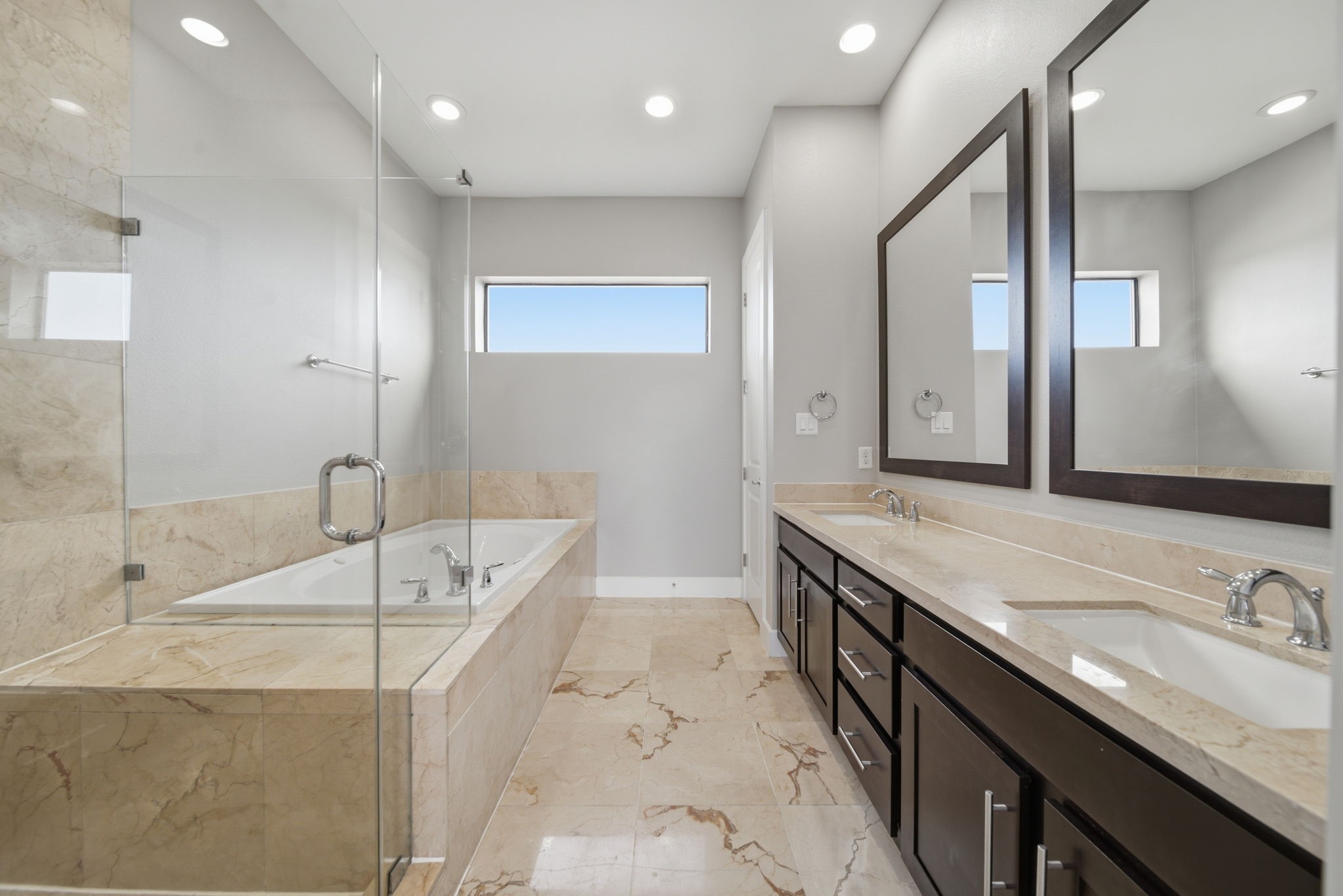 1814 Thompson Street Houston, TX 77007 - Photo 10 of 37 Luxurious primary bathroom showcasing a generous layout with dual vanities, sleek modern countertops, and refined marble tile finishes. A deep soaking tub and separate glass-enclosed shower create a spa-like retreat, enhanced by natural light filtering through a high window.