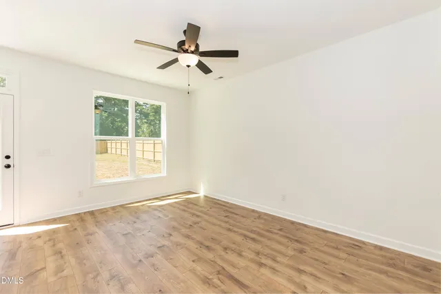 a view of an empty room with kitchen and a window