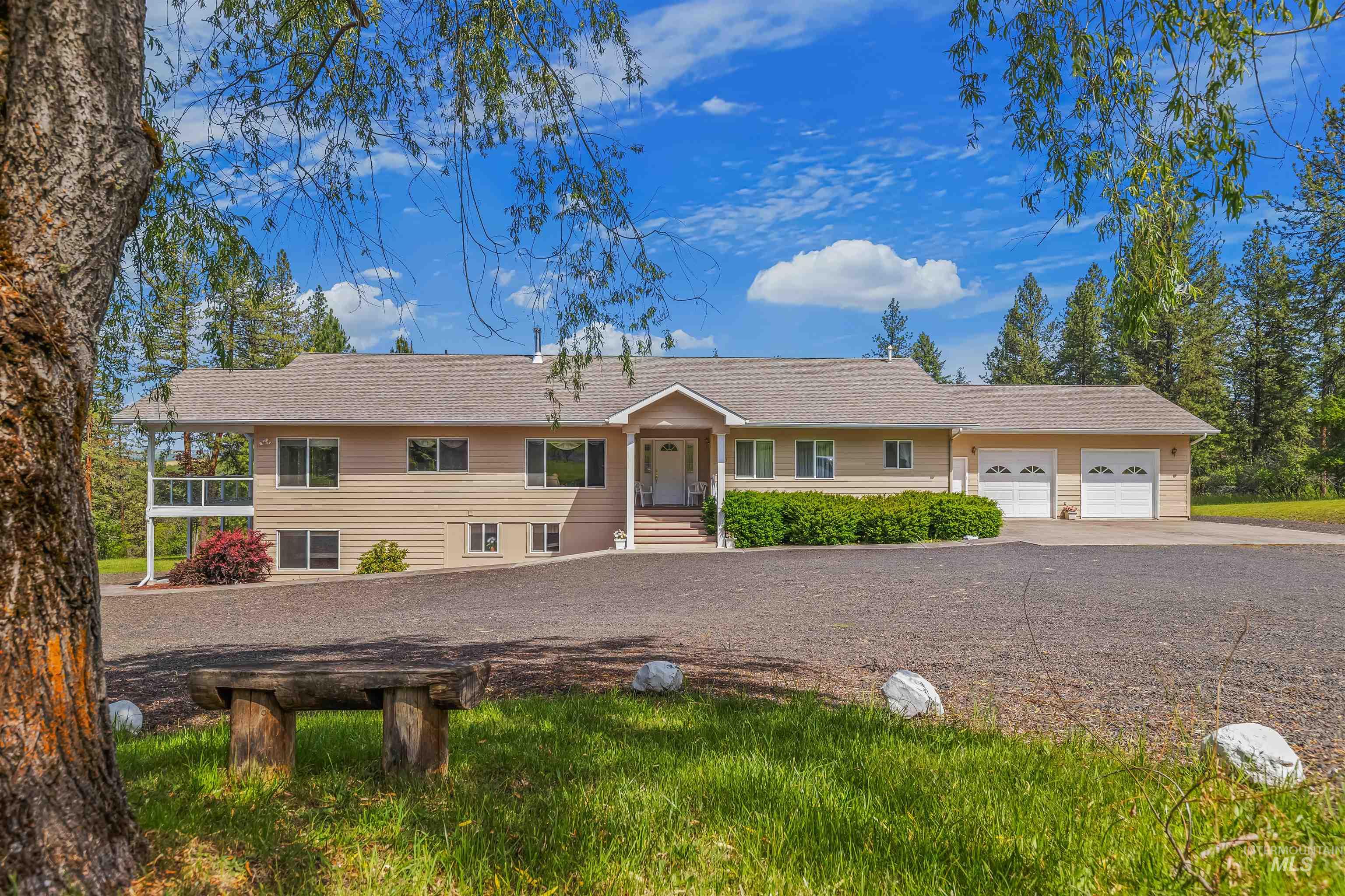 743 Wall Crk Road Stites, ID 83552 - Photo 4 of 48 Exterior featuring beige siding, a two-car garage, a gravel driveway, and a covered front porch entry