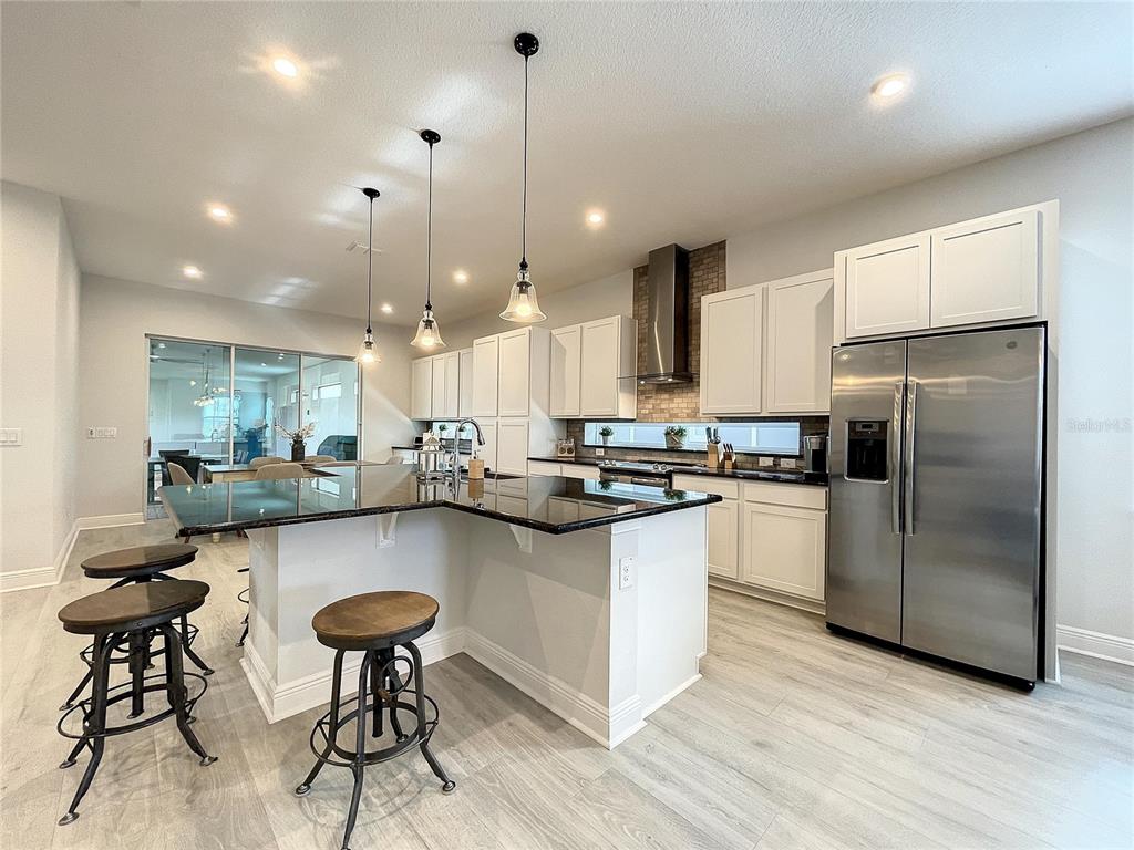 9062 Sperry Street Orlando, FL 32827 - Photo 9 of 44 a kitchen with stainless steel appliances granite countertop a sink a stove a refrigerator and island with wooden floor