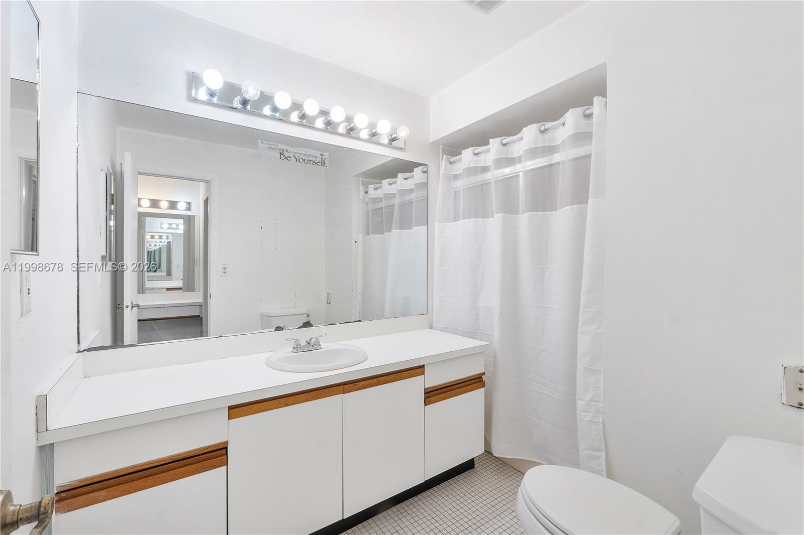 8243 Northwest 9th Street, Unit 7 Plantation, FL 33324 - Photo 19 of 30 a bathroom with a sink a toilet a mirror and shower curtain