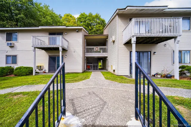 a view of a house with a yard and a large tree front of house
